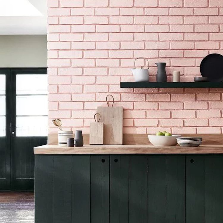 Cucina con pareti rosa cipria con mensole nere.