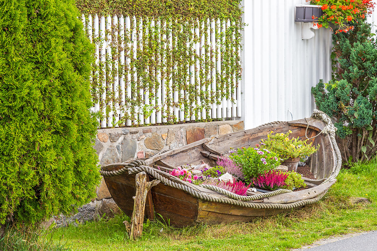 Vecchia barca decorata in giardino con dei fiori.