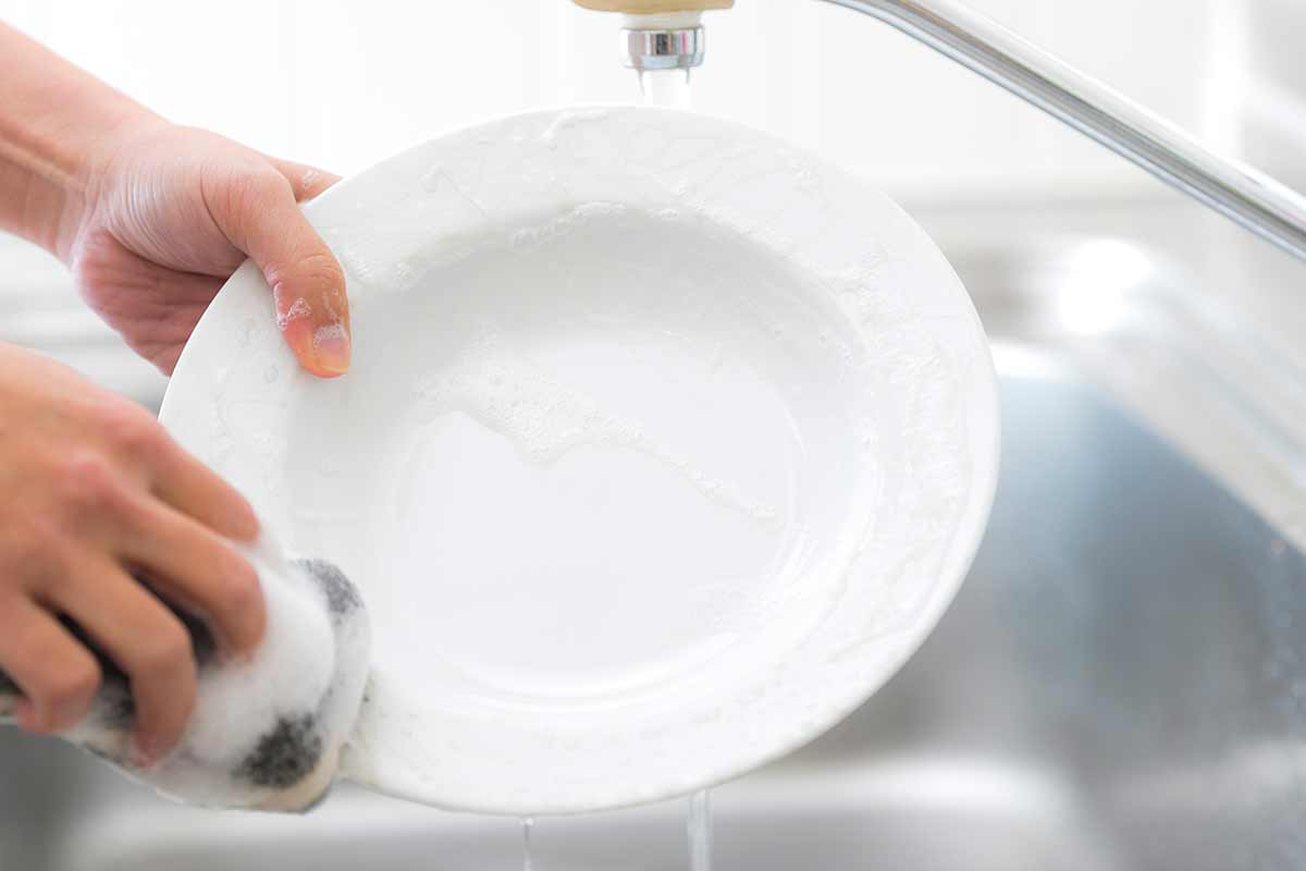 donna lavando i piatti con detersivo naturale