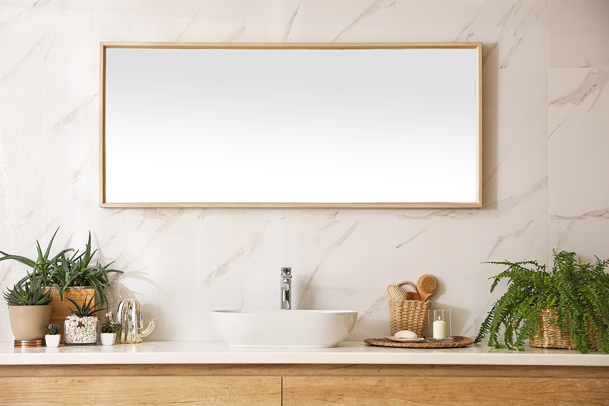 Specchio da bagno rettangolare con cornice in legno chiaro.