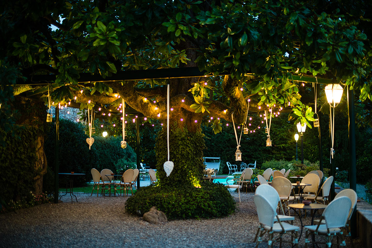 Terrazzo con Grande albero ombreggiante decorato con lucette di sera.