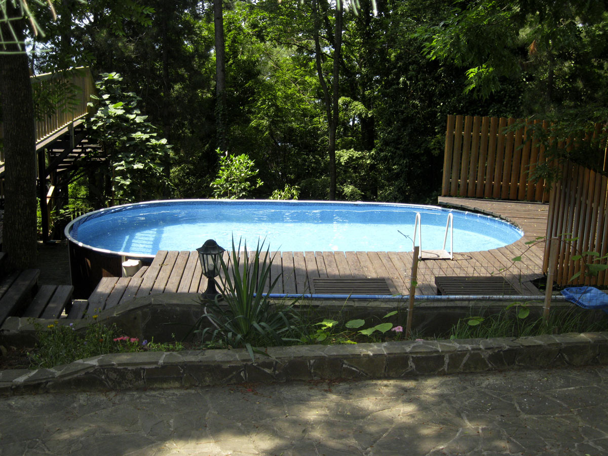 Grande piscina fuori terra ovale con soppalco in legno.